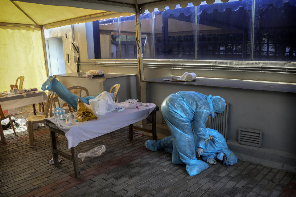 A health worker tends to her colleague who fainted due to exhaustion at a COVID-19 testing camp in New Delhi, India, Monday, April 27, 2020. (AP Photo/Manish Swarup)