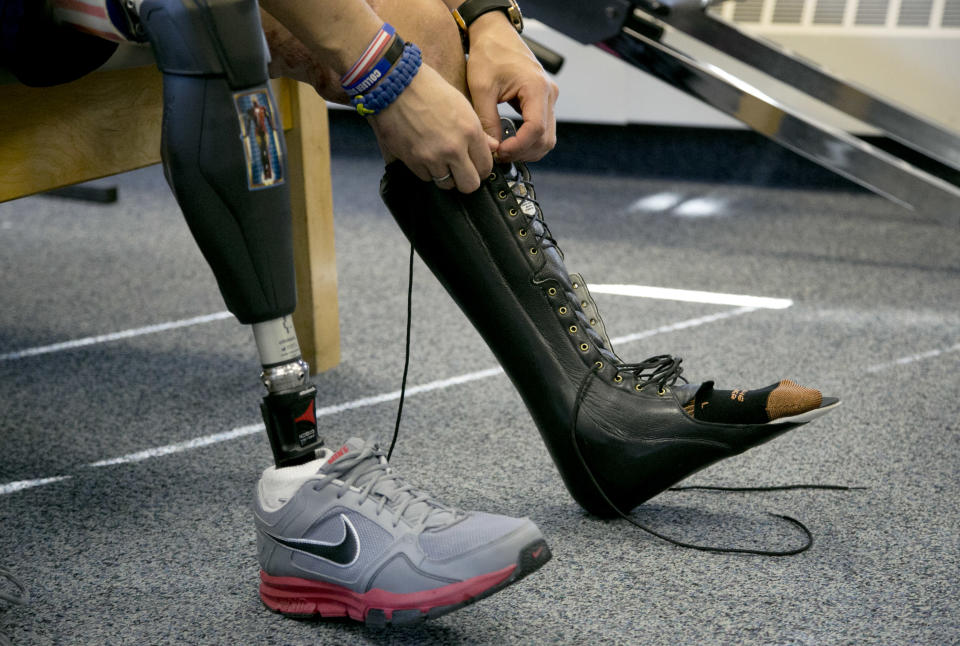 In this Thursday, April 3, 2014 photo, Boston Marathon bombing survivor Marc Fucarile, of Reading, Mass., ties laces on a support for his left leg after rehabilitation exercises at Spaulding Outpatient Center in Peabody, Mass. Fucarile lost his right leg in an explosion near the finish line of the 2013 race. (AP Photo/Steven Senne)