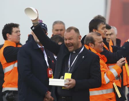 A priest celebrates after exchanging the papal cap with Pope Francis at Linate Airport in Milan, Italy, March 25, 2017. REUTERS/Stefano Rellandini