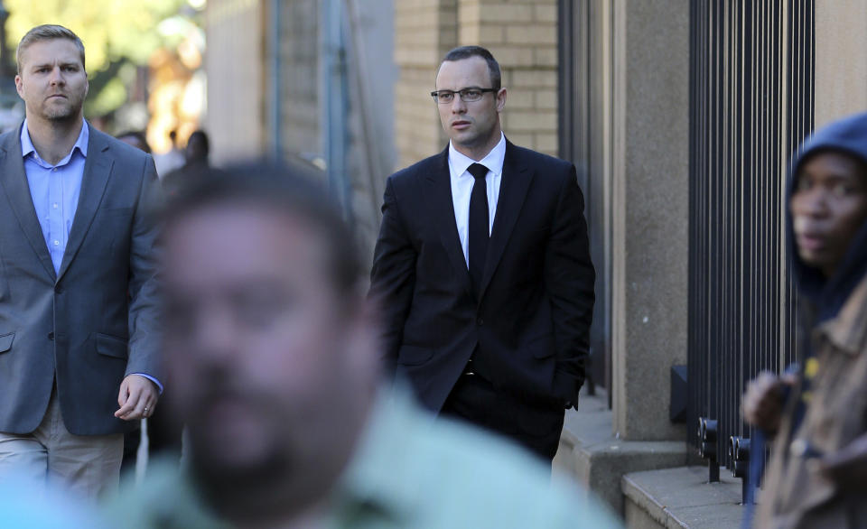 Oscar Pistorius, center, with an unidentified family member walks towards the high court in Pretoria, South Africa, Tuesday, May 13, 2014. Pistorius is charged with murder for the shooting death of his girlfriend, Reeva Steenkamp, on Valentines Day in 2013. (AP Photo/Themba Hadebe)