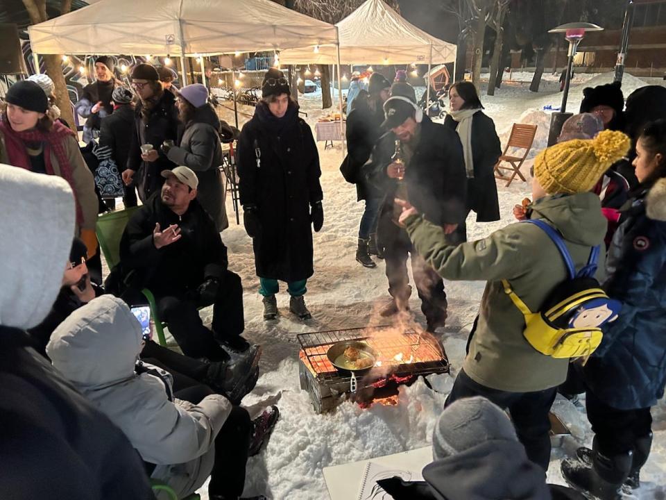 Participants of the winter storytelling event chat around the fire pit.