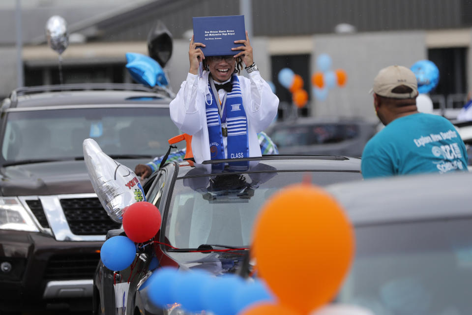 Graduate Cameron Magee holds up his diploma in celebration as the New Orleans Charter Science and Math High School class of 2020 holds a drive-in graduation ceremony as a result of the COVID-19 pandemic, outside Delgado Community College in New Orleans, Wednesday, May 27, 2020. Students and family got out of their cars to receive diplomas one by one, and then held a parade of cars through city streets. (AP Photo/Gerald Herbert)