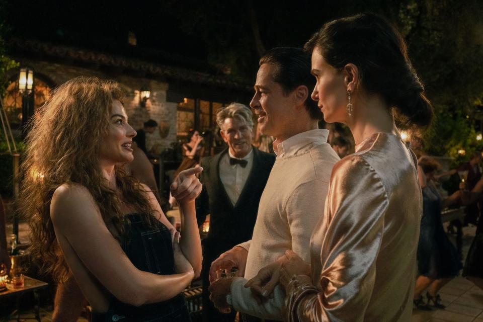 Silent movie star Nellie LaRoy (Margot Robbie, far left) and her dad Robert (Eric Roberts) run into Hollywood legend Jack Conrad (Brad Pitt) and his annoyed wife Estelle (Katherine Waterston) at a soiree in the period comedy drama "Babylon."