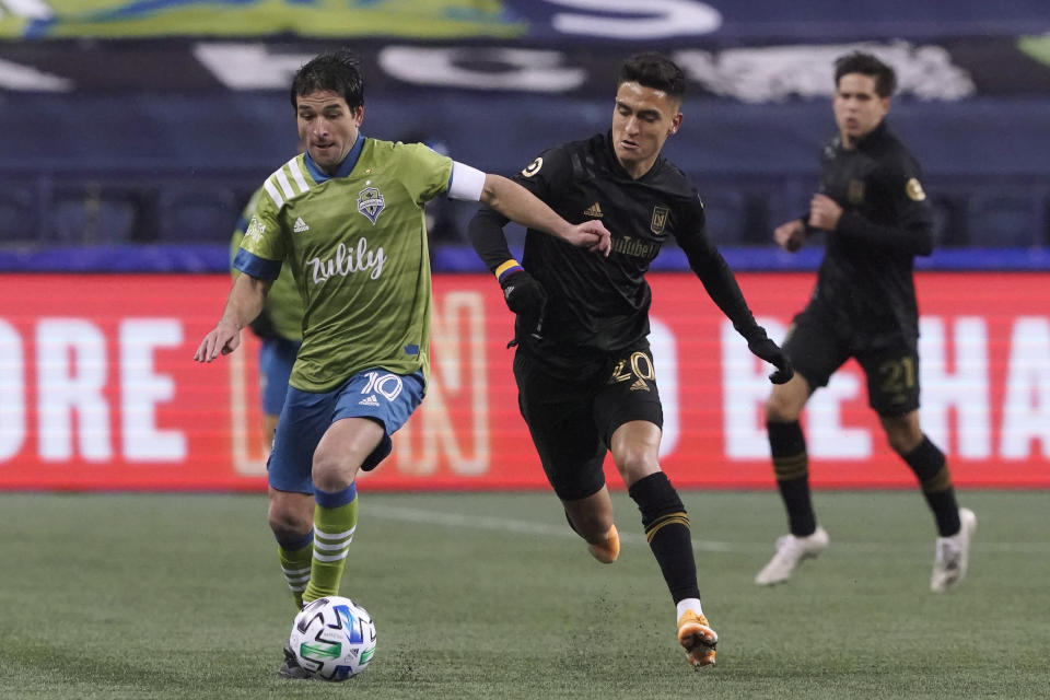 Seattle Sounders midfielder Nicolas Lodeiro (10) dribbles ahead of Los Angeles FC midfielder Eduard Atuesta during the first half of an MLS playoff soccer match Tuesday, Nov. 24, 2020, in Seattle. (AP Photo/Ted S. Warren)