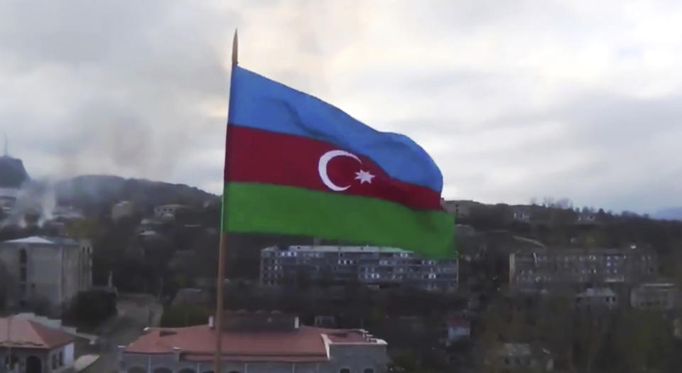 This photo taken from a video released by Azerbaijan's Defense Ministry on Monday, Nov. 9, 2020, shows Azerbaijan's national flag with the city of Shushi in the background, in the separatist region of Nagorno-Karabakh. President Ilham Aliyev said Sunday that Azerbaijani forces had taken control of the strategically important city in Nagorno-Karabakh, where fighting with Armenia has raged for over a month. (Azerbaijan's Defense Ministry via AP)