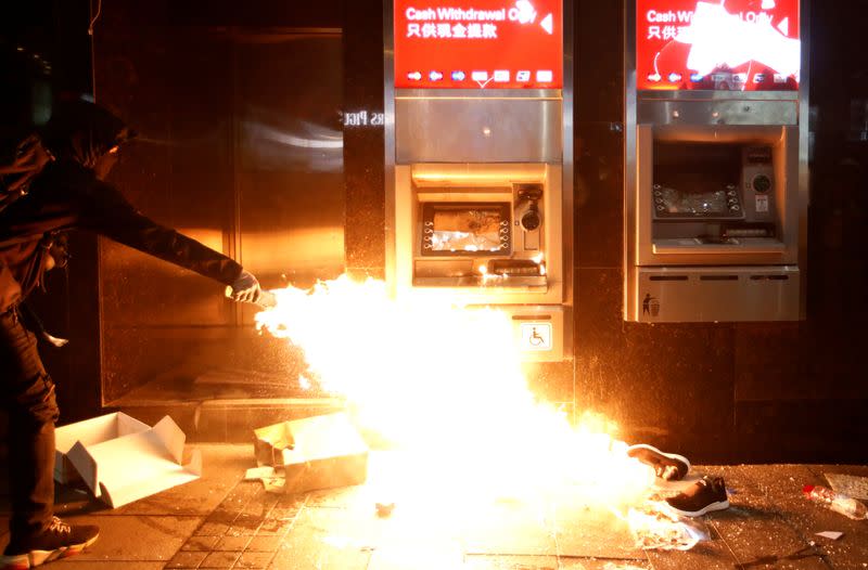 An anti-government protester feeds a flame near an ATM machine to vandalize it during an anti-government demonstration on New Year's Day to call for better governance and democratic reforms in Hong Kong