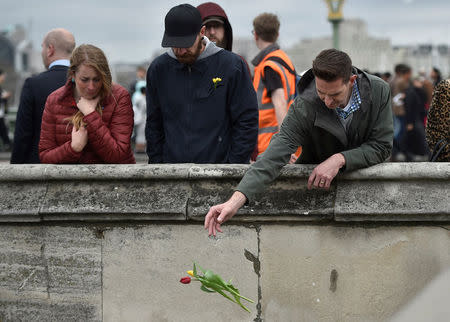 A man drops a flower into the River Thames during an event to mark one week since a man drove his car into pedestrians on Westminster Bridge then stabbed a police officer in London, Britain March 29, 2017. REUTERS/Hannah McKay