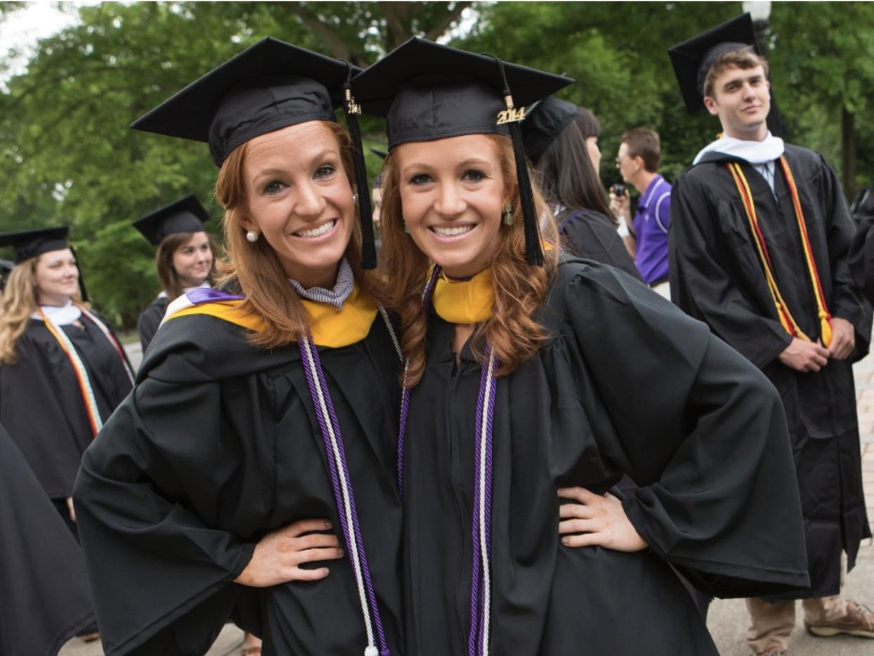 Identical twins Kayla and Kellie Bingham wearing graduation gowns