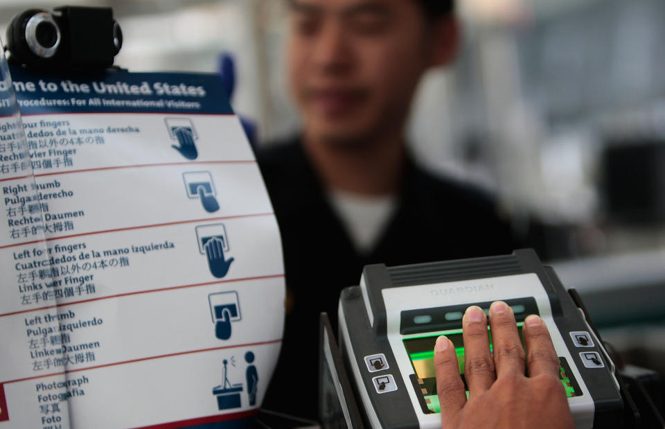 A traveler arriving from overseas is fingerprinted while his paperwork is checked by a border patrol official at the passport control line in Newark International Airport. Chris Hondros/Getty Images