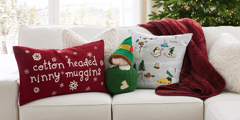 The "Cotton Headed Ninny Muggins" lumbar ($69), the elf shaped pillow ($69) and the elf printed pillow ($59) from the Pottery Barn X "Elf" collection. 