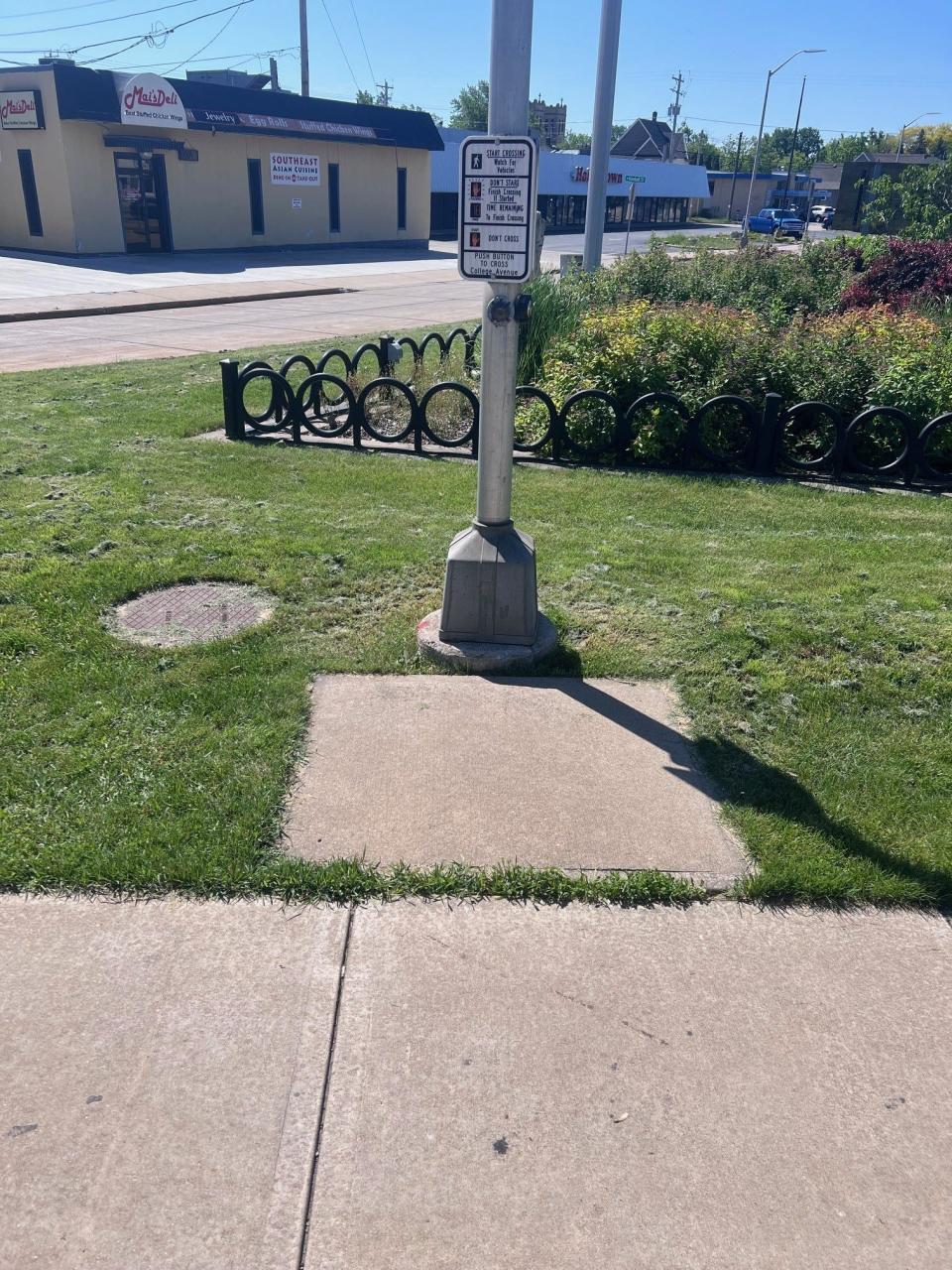 The button for the walk signals at the southeastern corner of College Avenue and Richmond Street in Appleton, Wis., is further than normal from the actual crosswalk, giving someone with limited mobility less time to cross the street. It is also set back from the main sidewalk, making wheel chair access difficult.