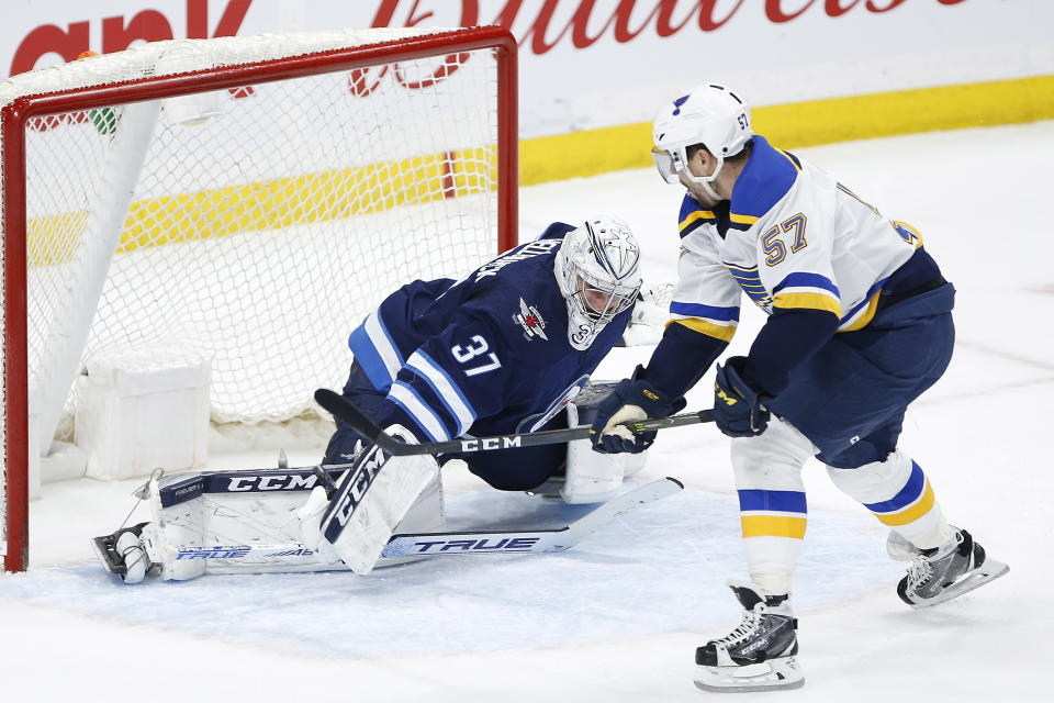 St. Louis Blues' David Perron (57) scores the winning goal in overtime against Winnipeg Jets goaltender Connor Hellebuyck (37) in NH hockey game action in Winnipeg, Manitoba, Friday, Dec. 27, 2019. (John Woods/The Canadian Press via AP)