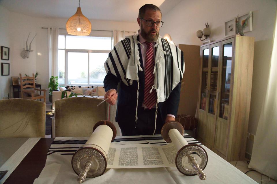 Alex Peterfreund, a co-founder of Dubai's Jewish community and its cantor, prepares to read from the Torah in Dubai, United Arab Emirates, Sunday, Aug. 16, 2020. Telephone service between the United Arab Emirates and Israel began working Sunday as the two countries opened diplomatic ties, part of a deal brokered by the U.S. that required Israel to halt its contentious plan to annex West Bank land sought by the Palestinians for a future state. (AP Photo/Jon Gambrell)