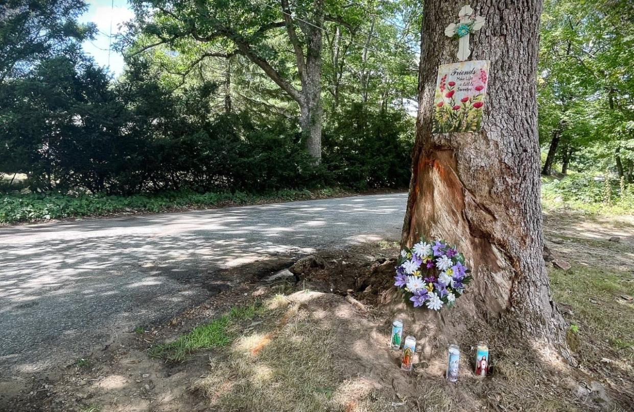 A memorial including candles and flowers is set up at the base of a tree on Glenview Street in Upton, where an 18-year-old from Uxbridge died in a crash Saturday.