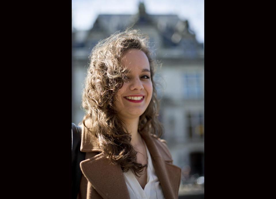 In this Wednesday April 16, 2014 photo, Charlotte van den Berg poses for a portrait outside the NIOD Institute for War, Holocaust and Genocide Studies, rear, in Amsterdam, Netherlands. Charlotte van den Berg was a 20-year-old college student working part-time in Amsterdam’s city archives when she and other interns came across a shocking find: letters from Jewish Holocaust survivors complaining that the city was forcing them to pay back taxes and late payment fines on property seized after they were deported to Nazi death camps. Van den Berg waged a lonely fight against Amsterdam’s modern bureaucracy to have the travesty publicly recognized. Now, largely due to her efforts, Amsterdam officials are considering compensating Holocaust survivors for the taxes and possibly other obligations, including gas bills, they were forced to pay for homes that were occupied by Nazis or collaborators while the rightful owners were in hiding or awaiting death in the camps. (AP Photo/Peter Dejong)