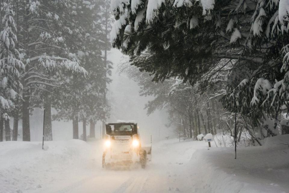 Snow is cleared from a road by a plow during a snowstorm