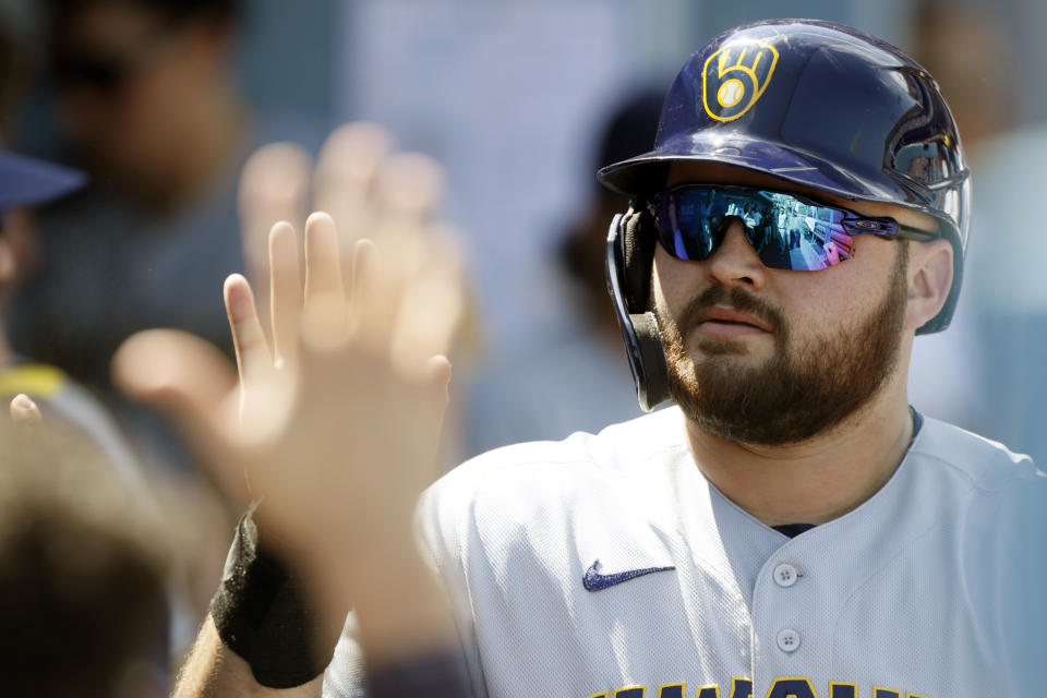 Milwaukee Brewers' Rowdy Tellez is congratulated by teammates on the bench after scoring on double by Avisail Garcia during the fourth inning of a baseball game against the Los Angeles Dodgers in Los Angeles, Sunday, Oct. 3, 2021. (AP Photo/Alex Gallardo)