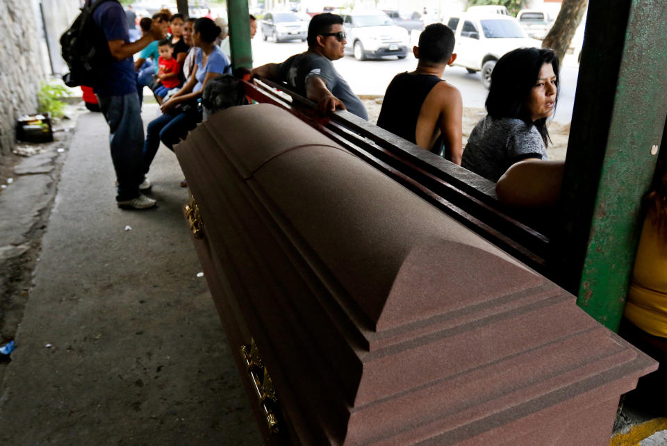 An empty coffin sits outside the morgue where people wait to identify and claim bodies in San Pedro Sula, Honduras, Tuesday, April 30, 2019. "Here you always have people who died violent deaths," said a funeral home worker who declines to give his name for fear of reprisals. (AP Photo/Delmer Martinez)