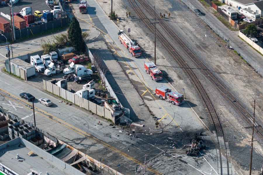 The tractor portion of a big rig, bottom right, is shown in an aerial view on Thursday, Feb. 15, 2024, in the Wilmington section of Los Angeles. Several Los Angeles firefighters were injured, two critically, when an explosion occurred as they responded to a truck with pressurized cylinders that were on fire early Thursday, authorities said. (AP Photo/William Liang)
