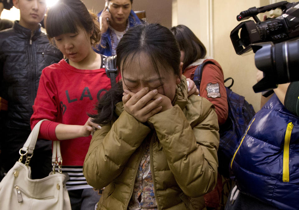 FILE - In this March 9, 2014 file photo, a Chinese relative of passengers aboard a missing Malaysia Airlines plane, center, cries as she is escorted by a woman while leaving a hotel room for relatives or friends of passengers aboard the missing airplane, in Beijing, China. Ten days after Malaysia Airlines Flight 370 disappeared with 239 people aboard, an exhaustive international search has produced no sign of the Boeing 777, raising an unsettling question: What if the airplane is never found? (AP Photo/Andy Wong, File)