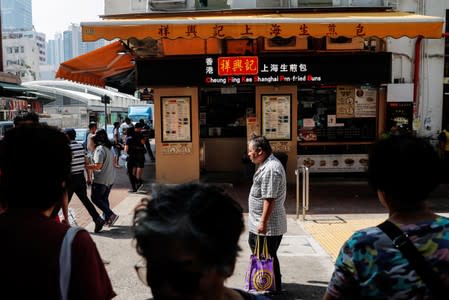 People walk past the exterior of a restaurant, the site where a student protester was shot by a policeman on Tuesday in Tsuen Wan, Hong Kong