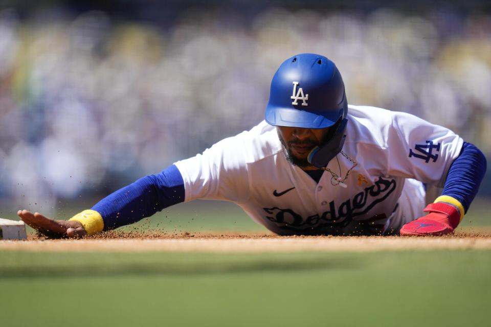 Dodgers' Mookie Betts dives safely back to first base during the third inning against the Atlanta Braves.