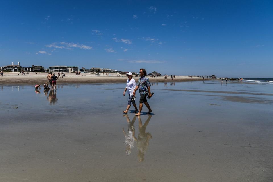 File: People walk on the Tybee Beach. (Photo by CHANDAN KHANNA / AFP)