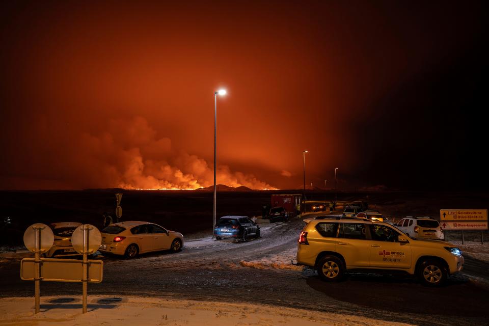 The road is blocked at the entrance of the road to Grindavík with the eruption in the background, in Grindavik on Iceland's Reykjanes Peninsula, Monday, Dec. 18, 2023. A volcanic eruption started Monday night on Iceland’s Reykjanes Peninsula, turning the sky orange and prompting the country’s civil defense to be on high alert.