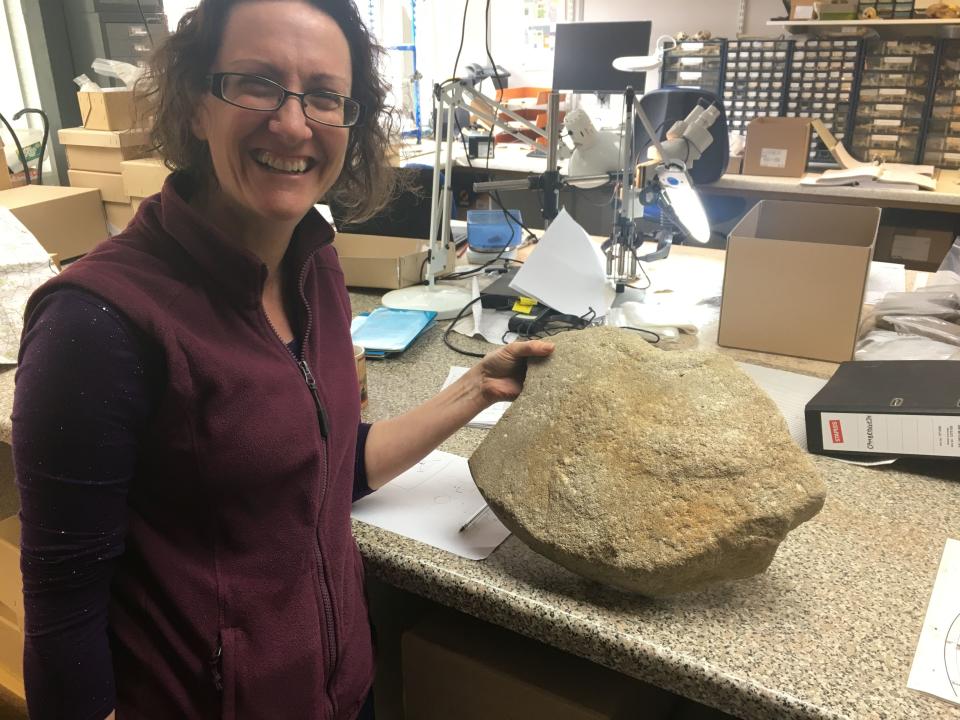 Dr Ruth Shaffrey of Oxford Archaeology with the rare Roman millstone (Highways England/ PA)