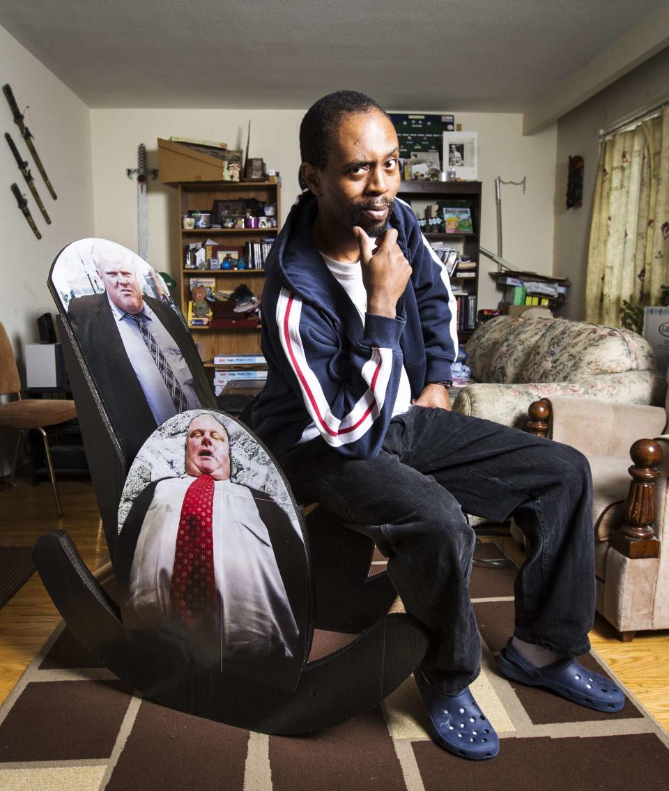 Nuwame poses on his " Mayor Rob Ford Crack Rocker", a rocking chair made completely of cardboard, in Mississauga