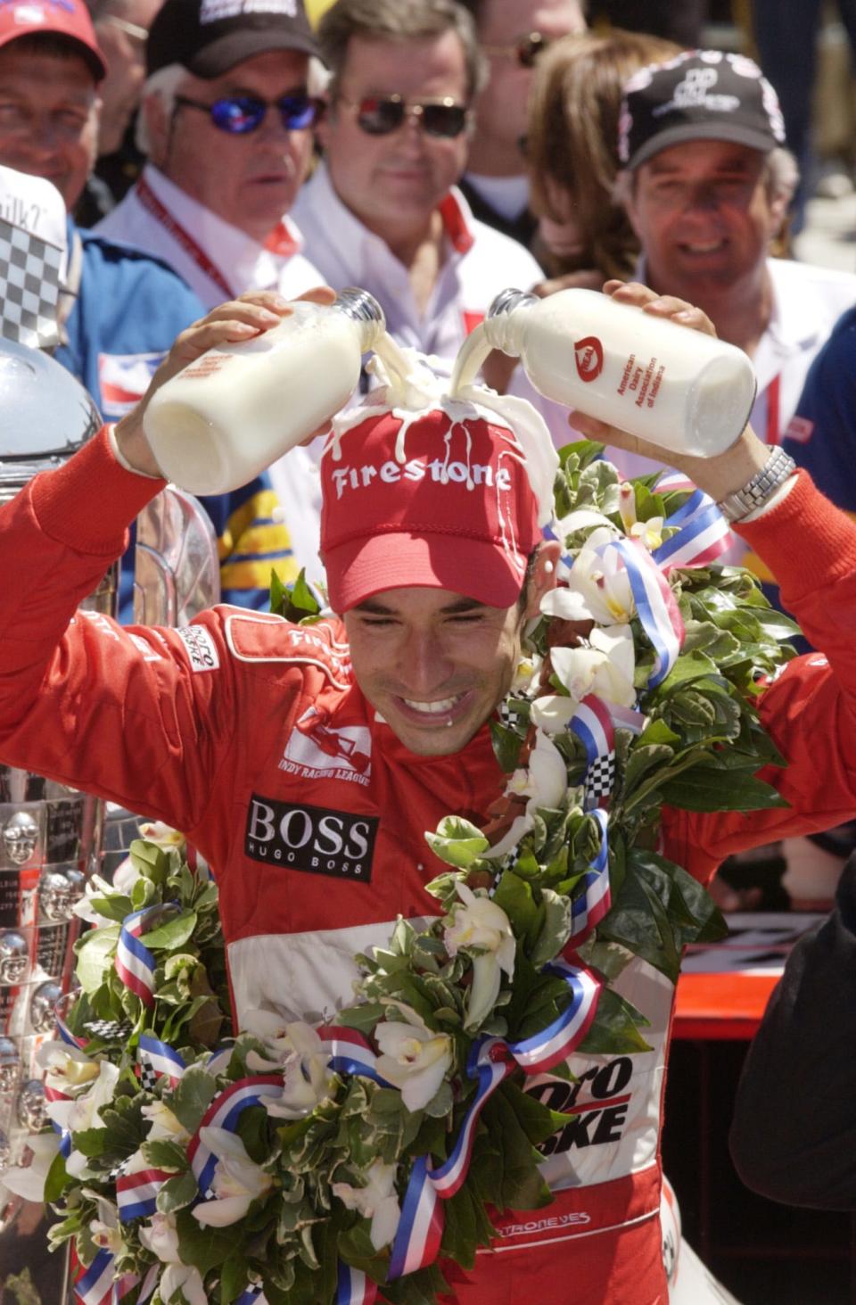 Helio Castroneves pours the ceremonial drink of milk over his head as he celebrates with teammates and fans on the Victory Lane after winning the 2002 Indianapolis 500.