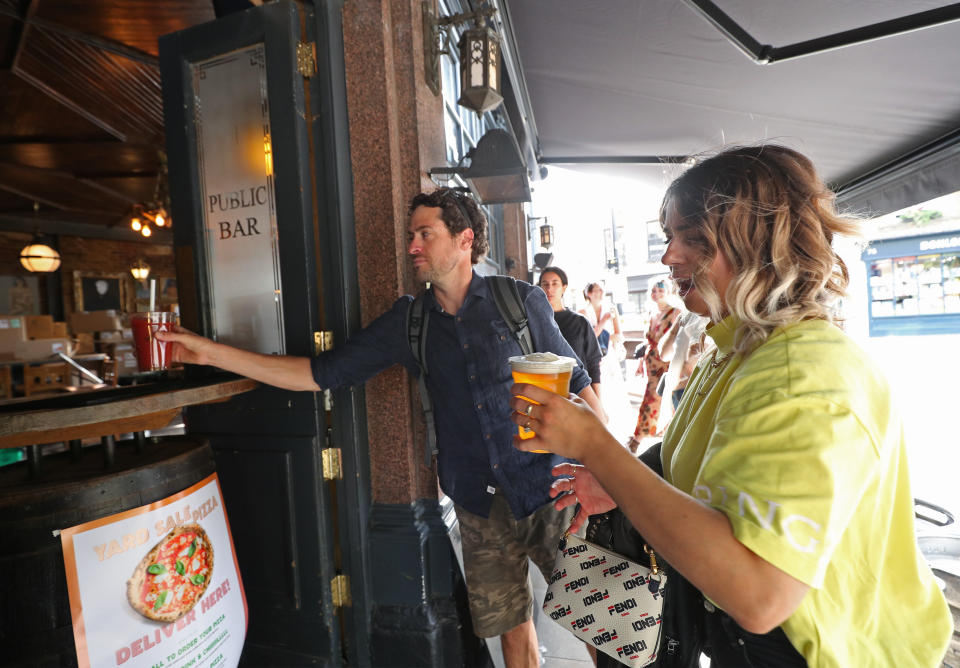 Customers are served takeaway drinks from the Cat & Mutton pub in Broadway Market, London, as further restrictions are lifted to bring England out of the coronavirus lockdown. (Photo by Yui Mok/PA Images via Getty Images)