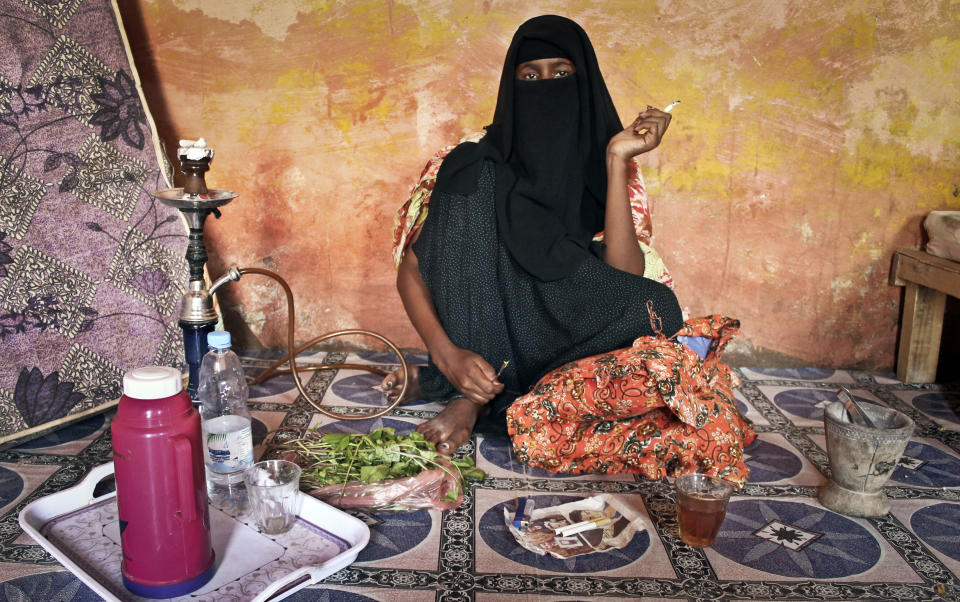 In this photo taken Tuesday, Sept. 18, 2012, prostitute Faduma Ali, who longs for the days when her pirate customers had money, chews the stimulant khat and smokes a cigarette at a house in the once-bustling pirate town of Galkayo, Somalia. The empty whisky bottles and overturned, sand-filled skiffs that litter this shoreline are signs that the heyday of Somali piracy may be over - most of the prostitutes are gone, the luxury cars repossessed, and pirates talk more about catching lobsters than seizing cargo ships. (AP Photo/Farah Abdi Warsameh)