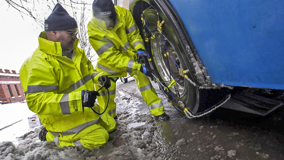 A crew from Pierce Transit puts tire chains on a metro bus in downtown Tacoma, Wash., Monday, February 11, 2019. Schools closed across Washington state and the Legislature canceled all hearings Monday with winter snowstorms pummeling the Northwest again. (Peter Haley/The News Tribune via AP)