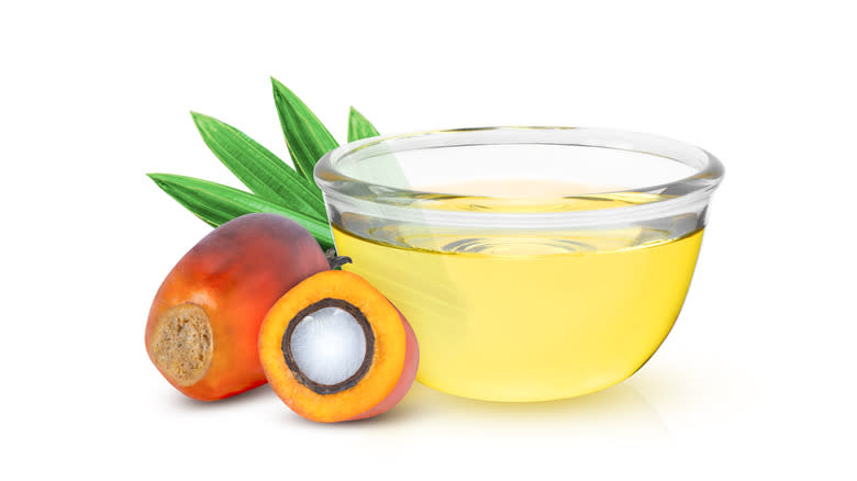 Palm fruit oil in a glass bowl with palm fruit beside