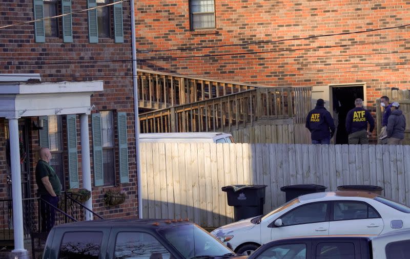 A neighbor watches as Law enforcement officers gather to investigate information arising the day after a downtown Nashville explosion, outside a duplex house in Antioch