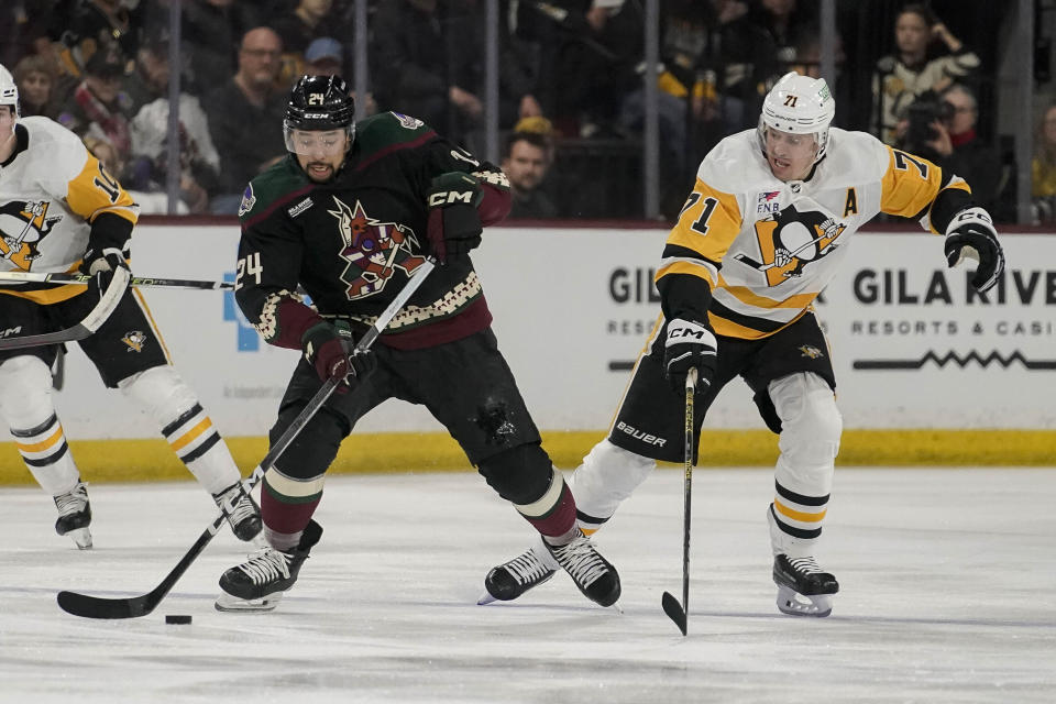 Arizona Coyotes' Matt Dumb, left, controls the puck against Penguins' Evgeni Malkin right, during the first period of an NHL hockey game, Monday, Jan. 22, 2024, in Tempe, Ariz. (AP Photo/Darryl Webb)