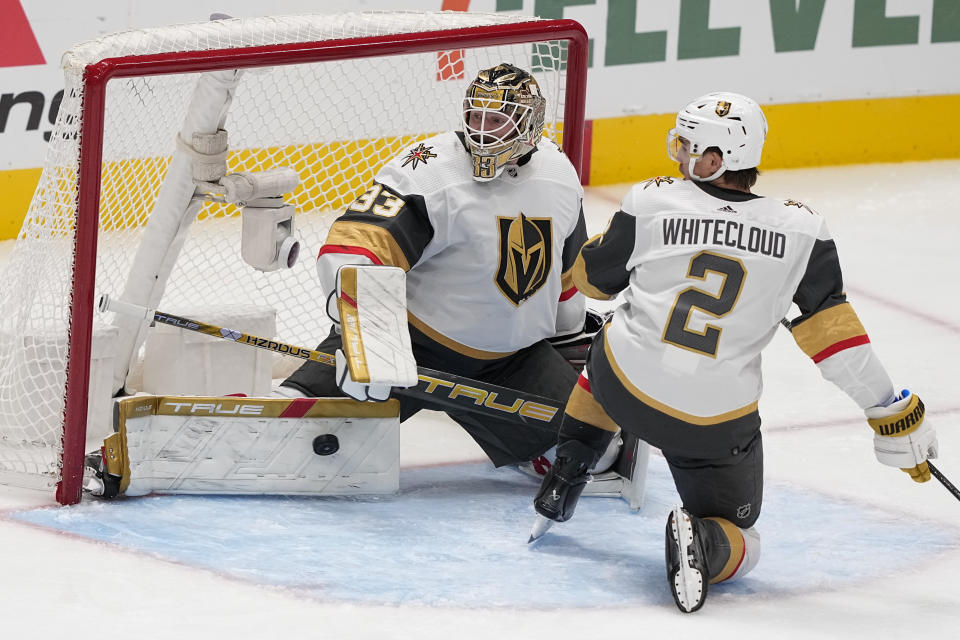 Vegas Golden Knights goaltender Adin Hill (33) stops a shot by the Dallas Stars as defenseman Zach Whitecloud (2) helps defend during the third period of an NHL hockey game, Wednesday, Nov. 22, 2023, in Dallas. (AP Photo/Tony Gutierrez)