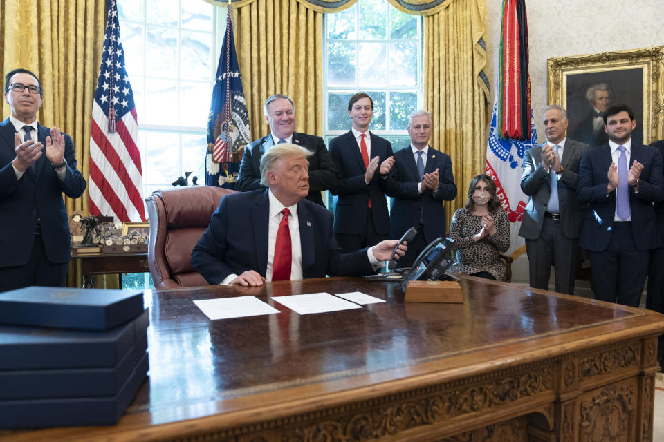 President Donald Trump hangs up a phone call with the leaders of Sudan and Israel, as Treasury Secretary Steven Mnuchin, left, Secretary of State Mike Pompeo, White House senior adviser Jared Kushner, National Security Adviser Robert O'Brien, and others applaud in the Oval Office of the White House, Friday, Oct. 23, 2020, in Washington. (AP Photo/Alex Brandon)