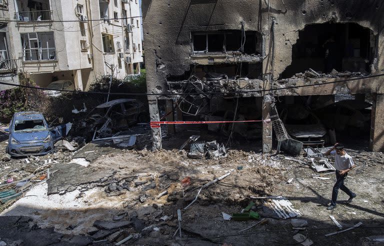 Un joven pasa frente a un edificio destruido por un cohete disparado desde Gaza en Petah Tikva, un suburbio de Tel Aviv, Israel, el 13 de mayo de 2021