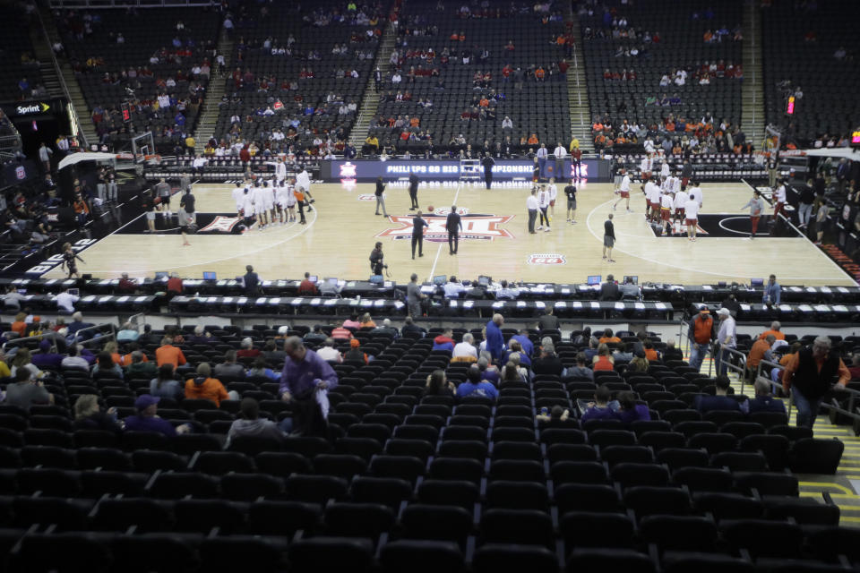 Fans watch Oklahoma State and Iowa State warm up before an NCAA college basketball game in the first round of the Big 12 men's basketball tournament in Kansas City, Kan., Wednesday, March 11, 2020. Fans will not be able to attend the tournament starting with the quarterfinal round. (AP Photo/Orlin Wagner)