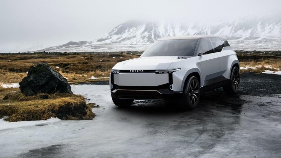 a white car parked on a road with snow covered mountains in the background