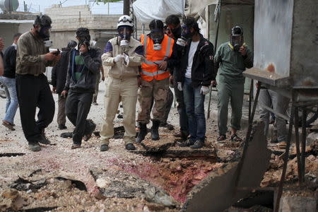 Civil Defence members wear gas masks near damaged ground in Ibleen village from what activists said was a chlorine gas attack, on Kansafra, Ibleen and Josef villages, Idlib countryside May 3, 2015. REUTERS/Abed Kontar