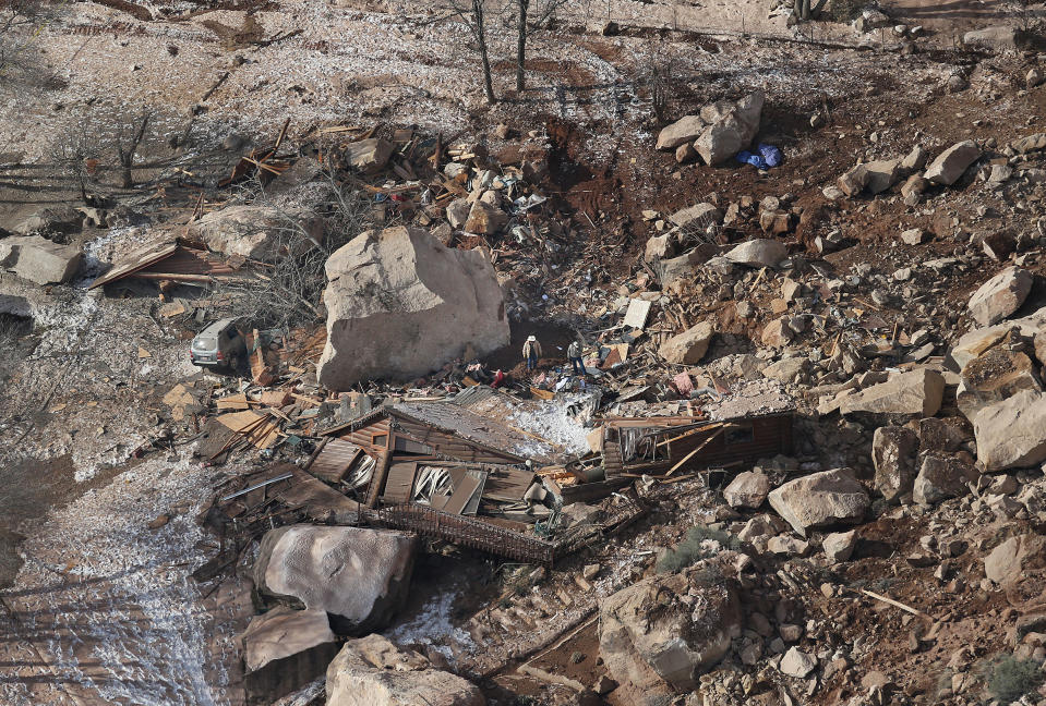 FILE - In this Dec. 13, 2013, file photo, officials survey the boulders from a rock slide that crushed a home and killed two people, in Rockville, Utah. Geologists are warning of the possibility of more rock slides in Utah like one in December that killed a middle-aged couple, flattening their cliff-side home near Zion National Park. The Utah Geological Society released its report Thursday, April 3, 2014 saying a massive sandstone slab near the one dislodged by rain and snow in December now threatens to crash and shatter onto the slope below. (AP Photo/The Deseret News, Tom Smart, File) SALT LAKE TRIBUNE OUT; MAGS OUT