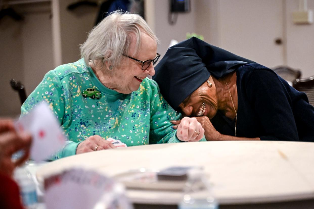 Sue Forbrush, right, leans over and laughs with Jan Gee while playing cards Thursday, April 11, 2024, at Gorsline Runciman Funeral Homes in East Lansing. The game day is one of several Living Information For Today events that brings together those dealing with loss to offer social support.