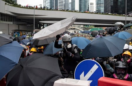 Demonstrators take cover as police fires tear gas during a protest in Hong Kong