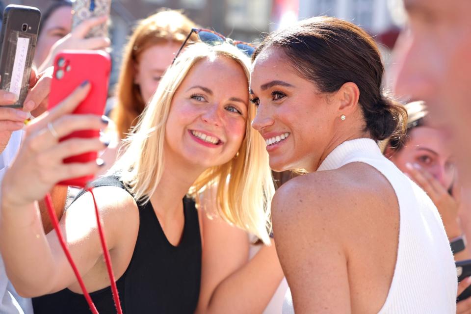 DUSSELDORF, GERMANY - SEPTEMBER 06: Meghan, Duchess of Sussex takes selfies with well-wishers outside the town hall during the Invictus Games Dusseldorf 2023 - One Year To Go events, on September 06, 2022 in Dusseldorf, Germany. The Invictus Games is an international multi-sport event first held in 2014, for wounded, injured and sick servicemen and women, both serving and veterans. The Games were founded by Prince Harry, Duke of Sussex who's inspiration came from his visit to the Warrior Games in the United States, where he witnessed the ability of sport to help both psychologically and physically. (Photo by Chris Jackson/Getty Images for Invictus Games Dusseldorf 2023)