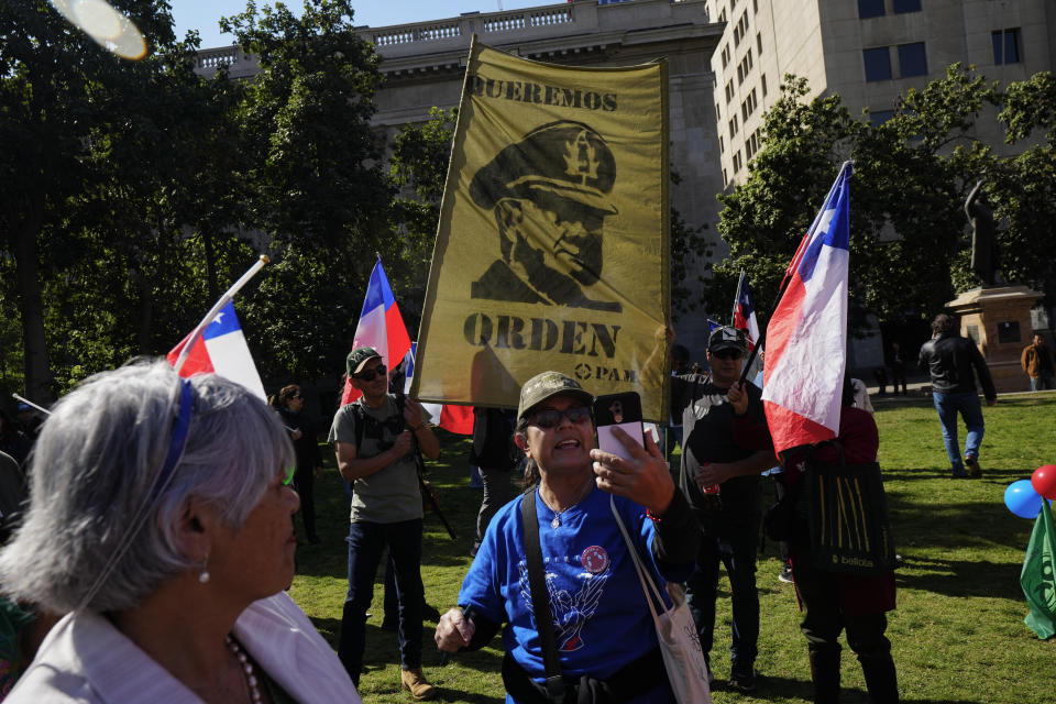 People hold a banner with an image of Gen. Augusto Pinochet and a message that reads in Spanish: "We want order", during a demonstration seeking justice for police officers killed in the line of duty, in Santiago, Chile, Saturday, April 27, 2024. Three police officers were killed early Saturday, in Cañete, Chile's Bío Bío region. (AP Photo/Esteban Felix)