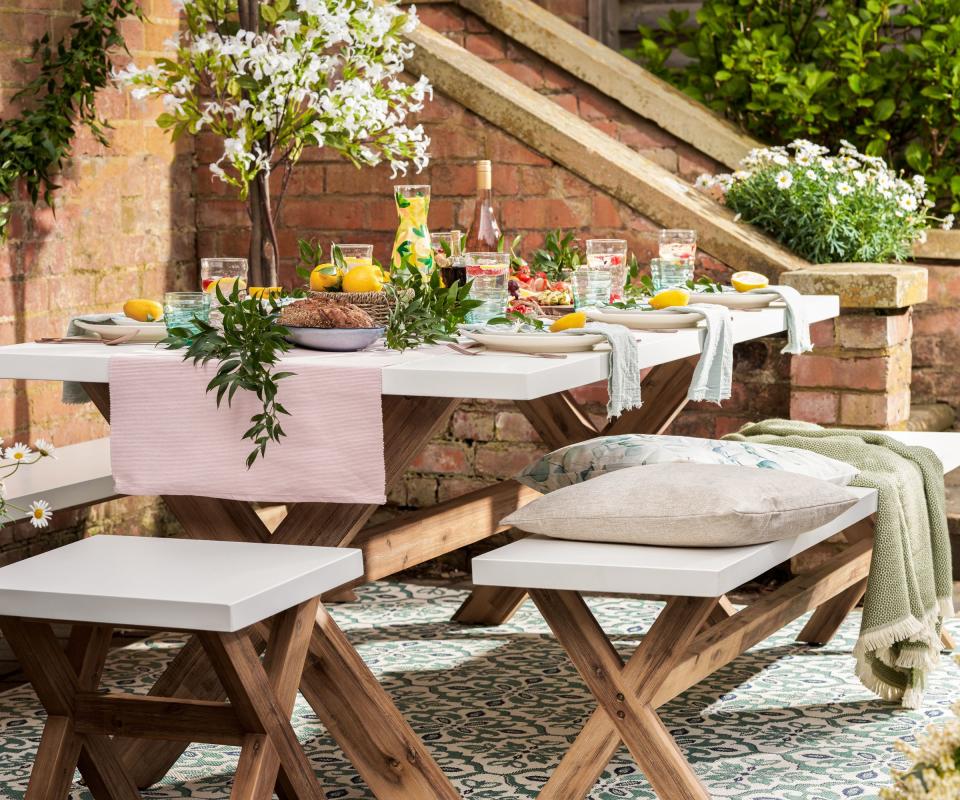 Vanesa Flatweave Blue Area Rug beneath a fully laid outdoor dining table in a sunny garden