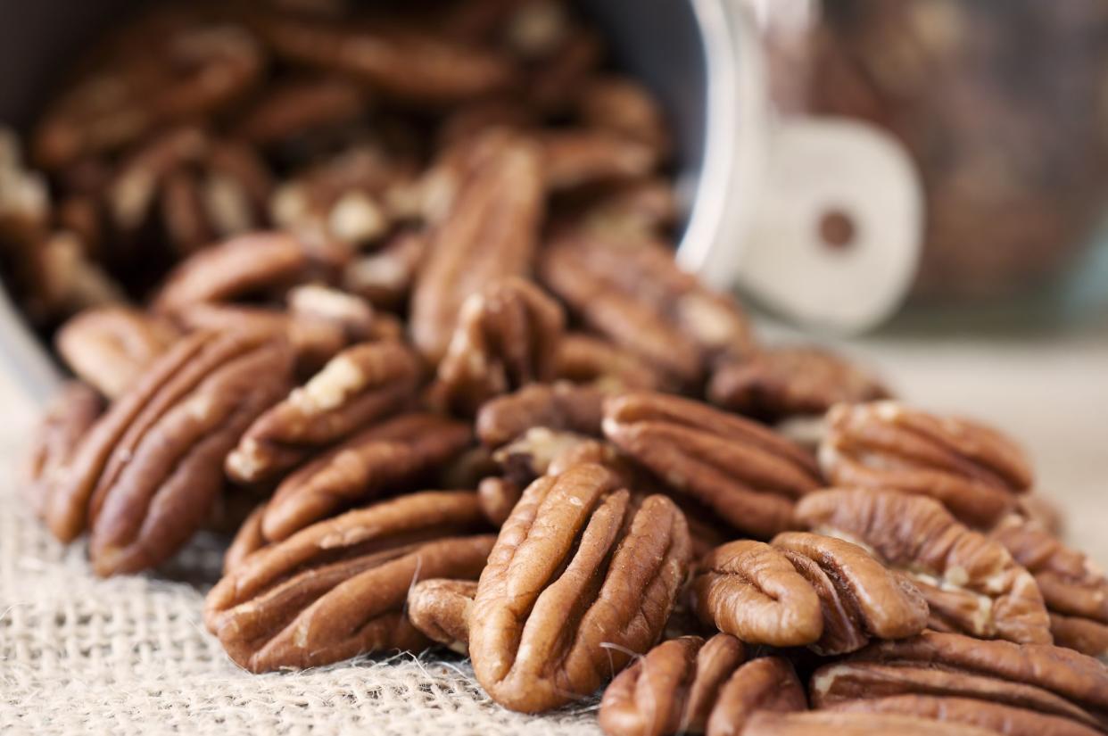 Pecan halves and a measuring cup in the background.Similar images: